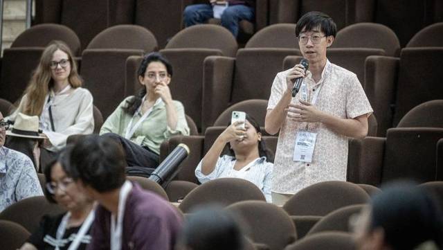 Lance holding a microphone during a discussion at AIED 2025 in Palermo, Italy.
